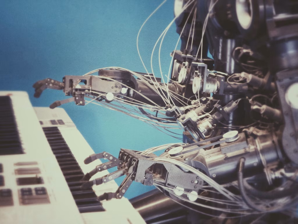 A robotic arm with exposed wires plays a keyboard against a blue backdrop, illustrating AI's potential in music composition. - midnightrebels.com