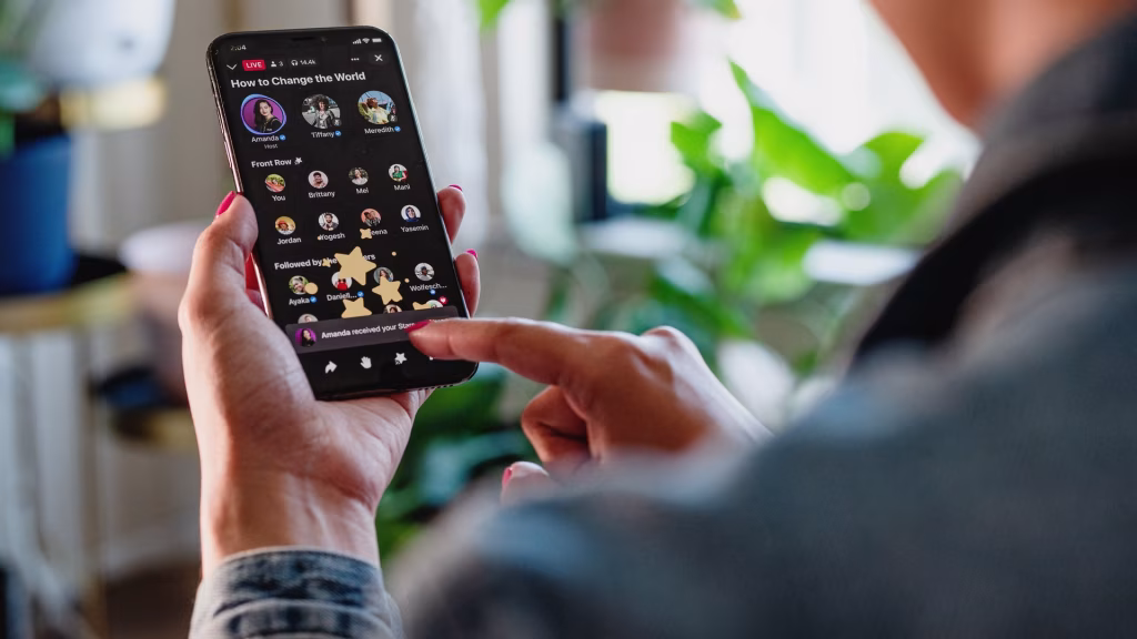 A person holds a smartphone displaying a Facebook Live audio room with profile images and the text "How to Change the World," illustrating Facebook's entry into the audio content space. - midnightrebels.com