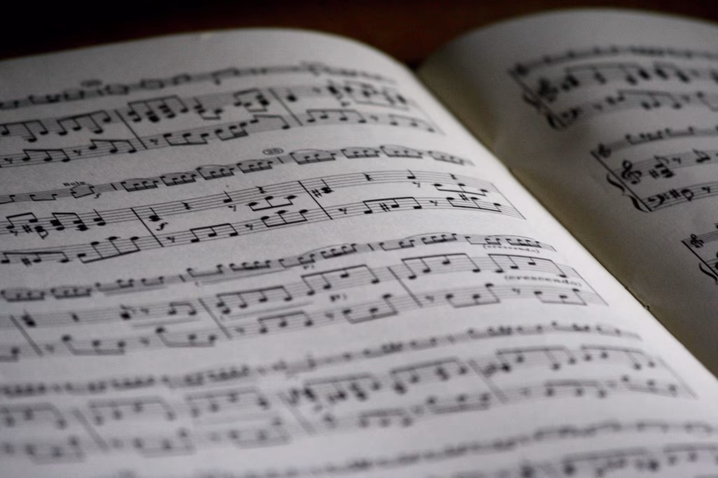 Open sheet music book displaying musical notes on white pages, representing the potential therapeutic benefits of music for dementia patients. - midnightrebels.com