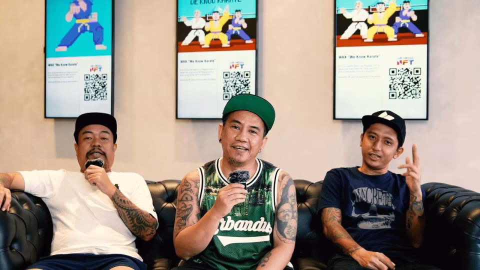 The band "We Know Karate," Philippines' first music NFT band, poses in front of screens displaying their karate-themed NFT art and QR codes. - midnightrebels.com