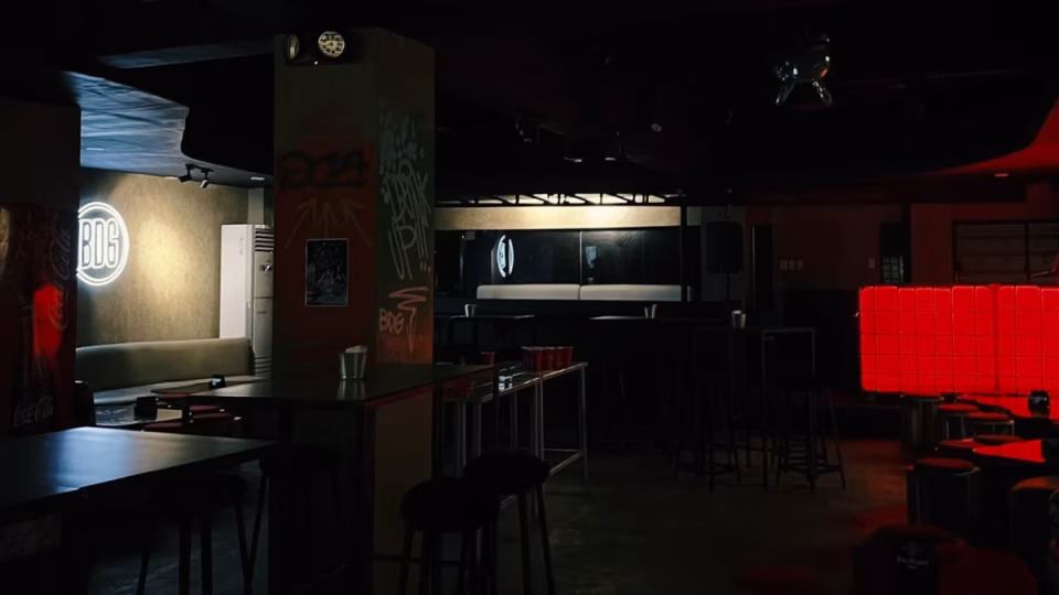 Interior view of Club Bodega in Zamboanga City, featuring low lighting, tables, chairs, a 'BDG' neon sign, and graffiti art on the walls, evoking a modern and intimate nightlife experience. - midnightrebels.com
