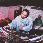 A Filipino DJ expertly maneuvers a Pioneer mixer at a club, surrounded by a dancing crowd, emphasizing the vibrant nightlife scene. - midnightrebels.com