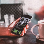 Person holding a smartphone displaying a social media post advertising a local DJ event, next to a cup of tea, illustrating the shift towards digital flyer promotion within the nightlife scene. - midnightrebels.com