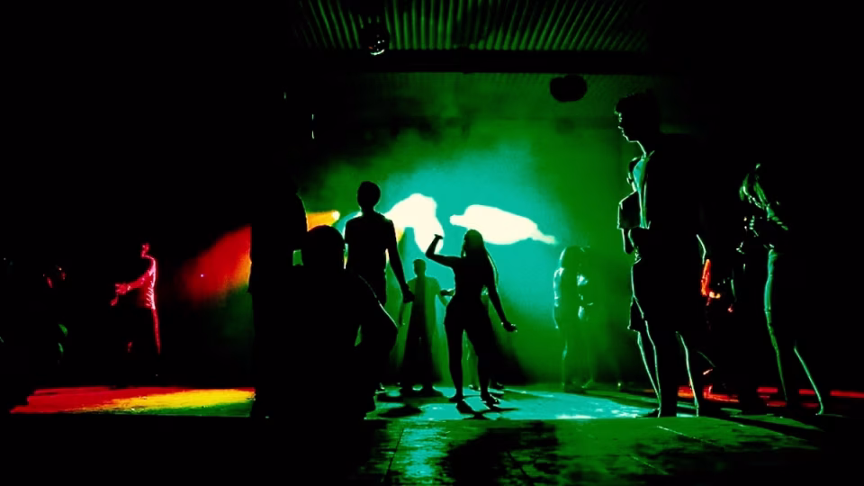 Silhouette of a small crowd dancing under colorful green and white stage lights at a nightclub, showcasing that any crowd size can have great energy when a DJ is passionate. - midnightrebels.com