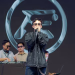 A singer performs with a microphone in front of the RVERB logo, accompanied by DJs at a music event in Cebu. - midnightrebels.com