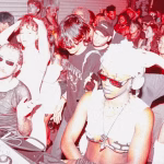 A densely packed underground rave scene glows with red-tinged lighting, featuring DJs and diverse young people dancing and enjoying the music. - midnightrebels.com