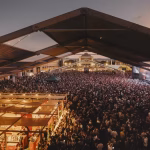 A wide shot captures a massive crowd gathered under a large tent structure at the Sónar music festival at dusk. - midnightrebels.com
