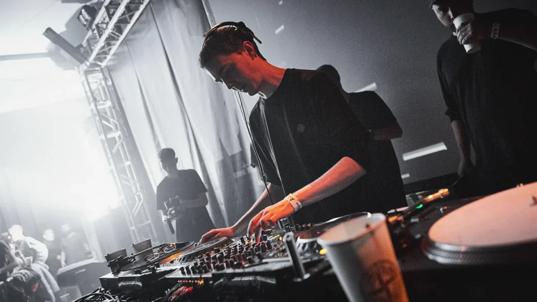 DJ performing at music festival with equipment in grayscale image.