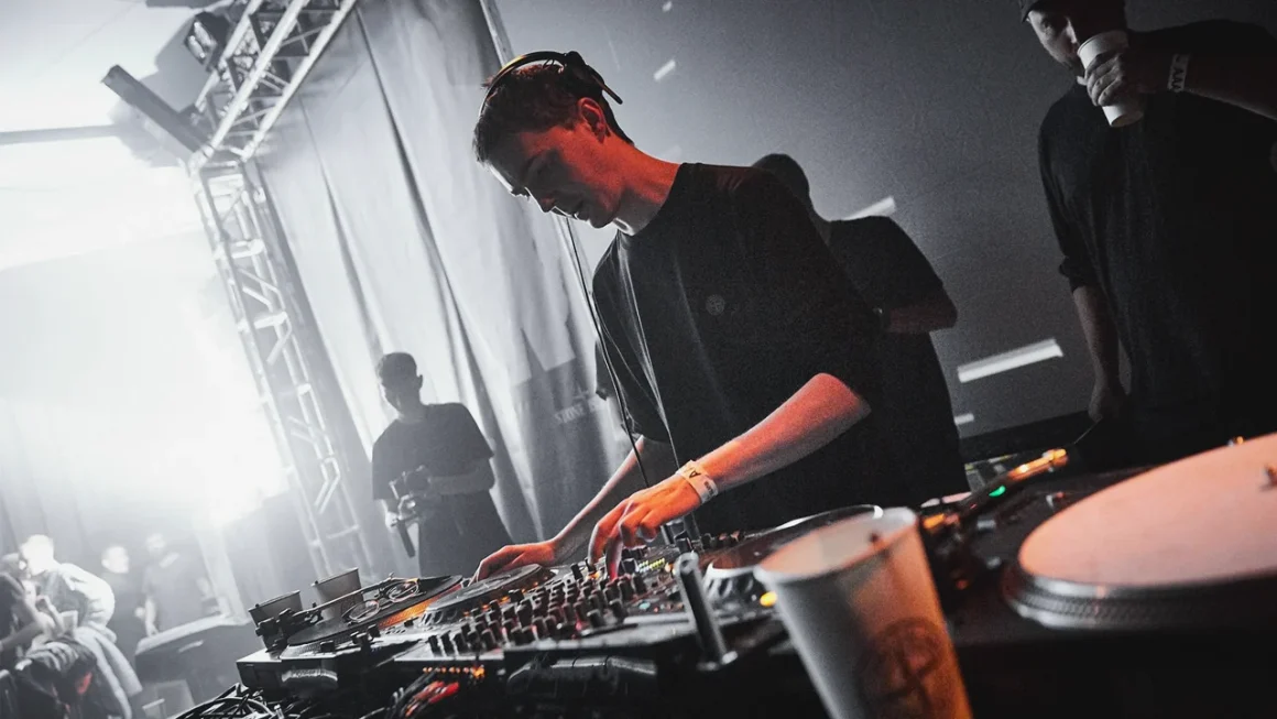DJ performing at music festival with equipment in grayscale image.