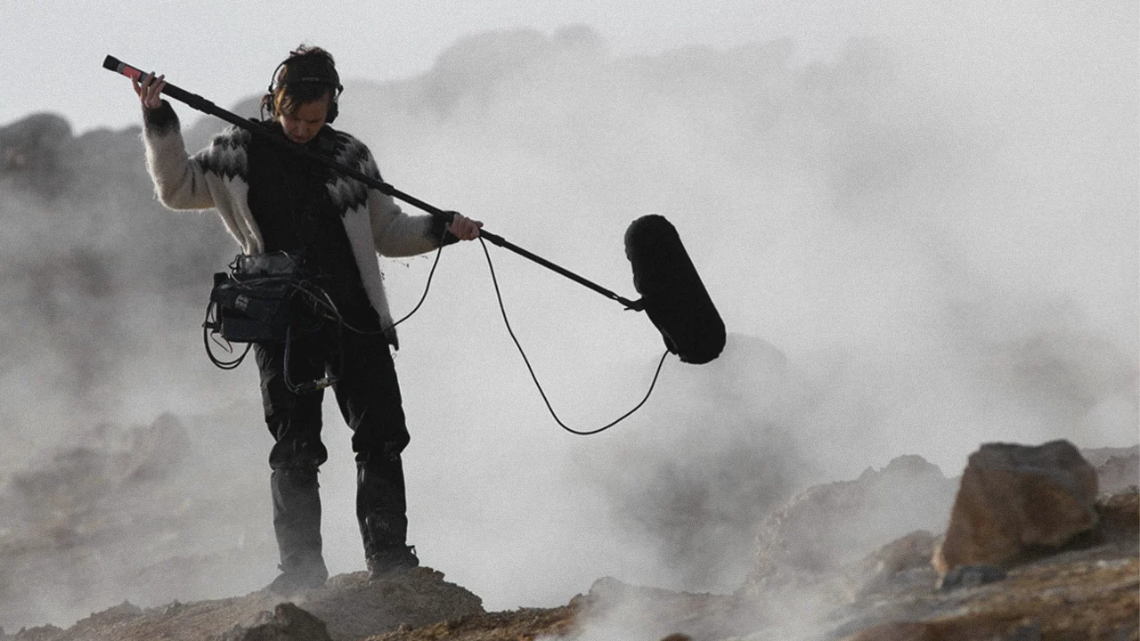Audio engineer recording sound on windy, misty Iceland landscape.