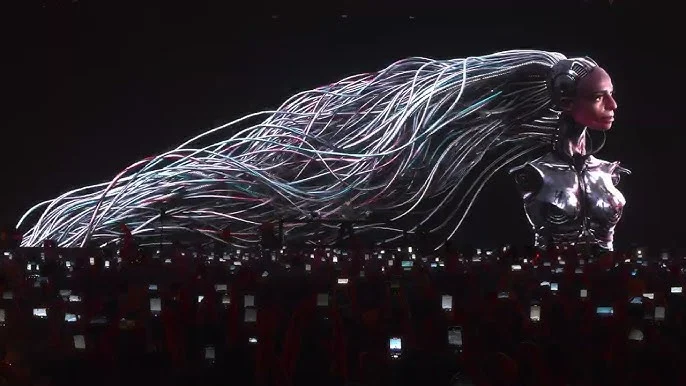 Concert crowd filming FKA Twigs robotic bust with cable hair.