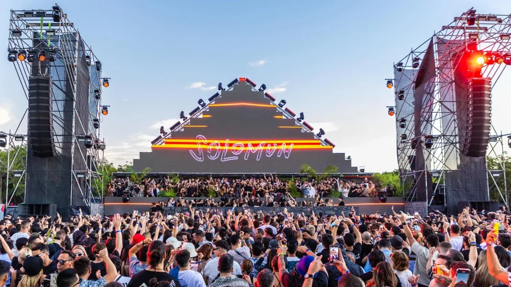 Solomun live music festival, large crowd, pyramid stage with neon lights.