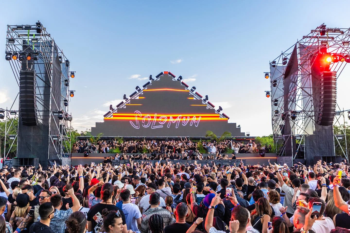 Solomun live music festival, large crowd, pyramid stage with neon lights.