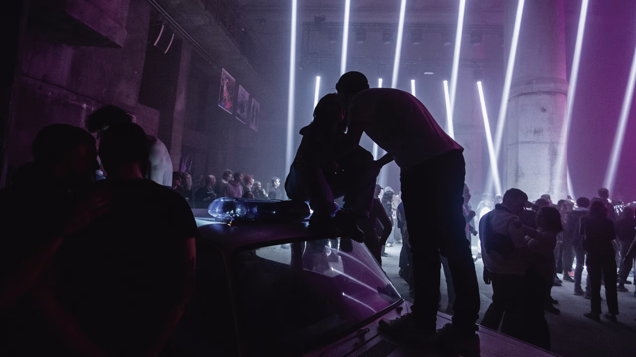 Crowded party with people on police car, lights background.