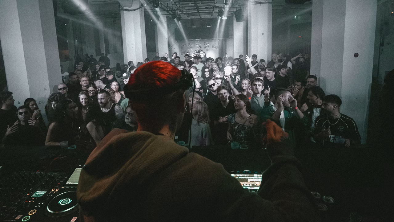 DJ performing for a large crowd in a club.