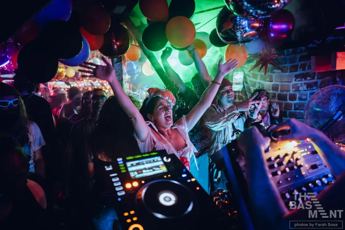 Partygoers celebrate at The Basement nightclub with DJ playing music.