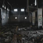 Abandoned destroyed warehouse interior with debris rubble and broken windows depicting urban decay and devastation