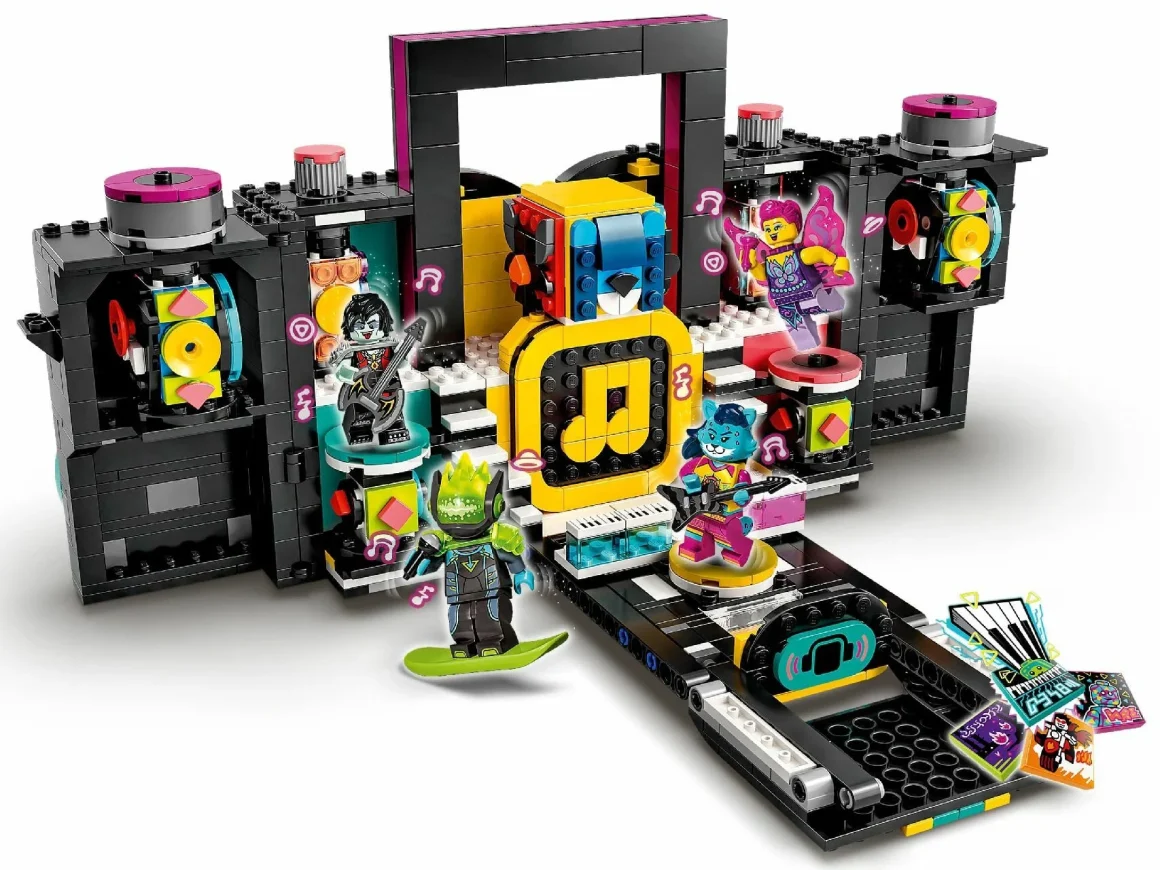 A colorful LEGO music stage set featuring various characters, musical instruments, and vibrant decorations. The scene includes a guitarist, a singer with a microphone, and a character on a skateboard, all in front of a backdrop with music notes and sound elements.