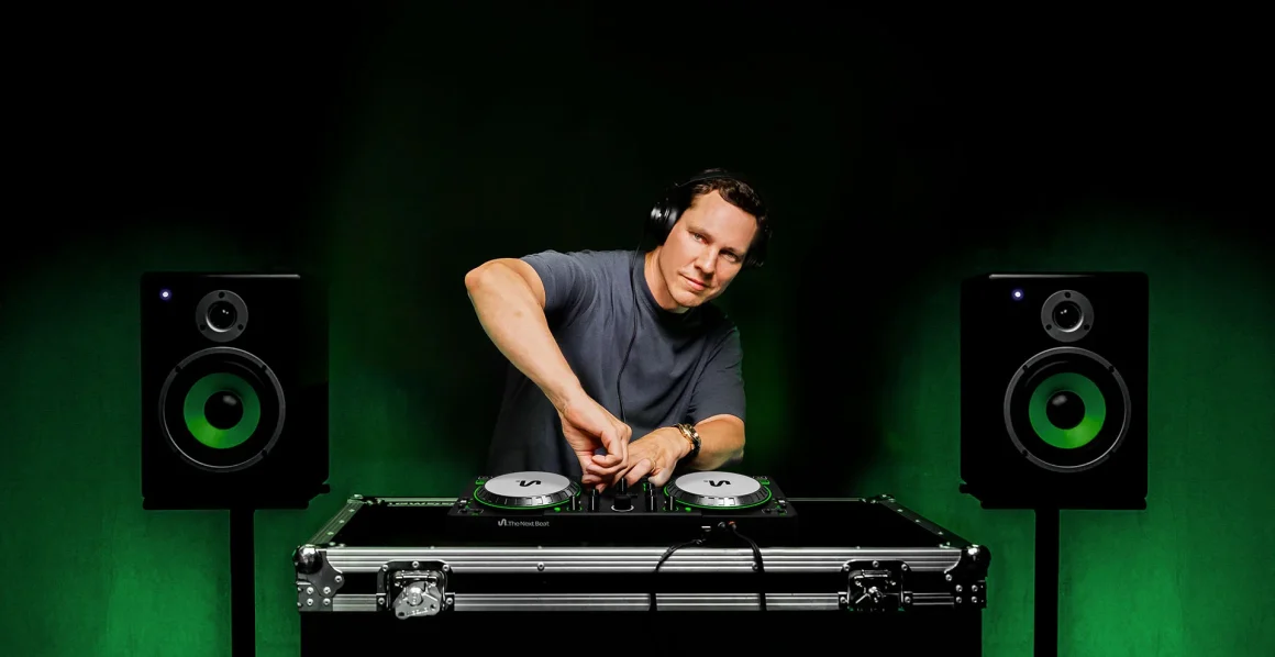 A DJ mixing music at a setup with turntables and speakers against a dark green background.