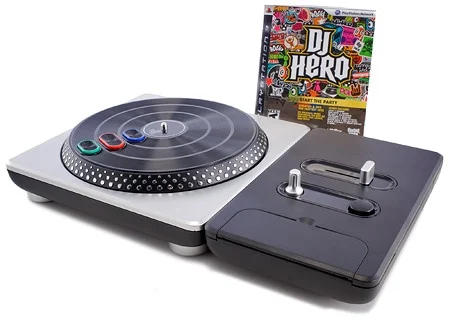 A DJ Hero game console setup featuring a turntable controller with colored buttons and a game box in the background.