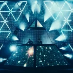 Electronic music concert stage with Daft Punk behind a pyramid-shaped LED screen and geometric light patterns