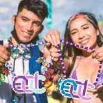 Two festival attendees smiling and holding colorful beaded necklaces with pixel art pendants