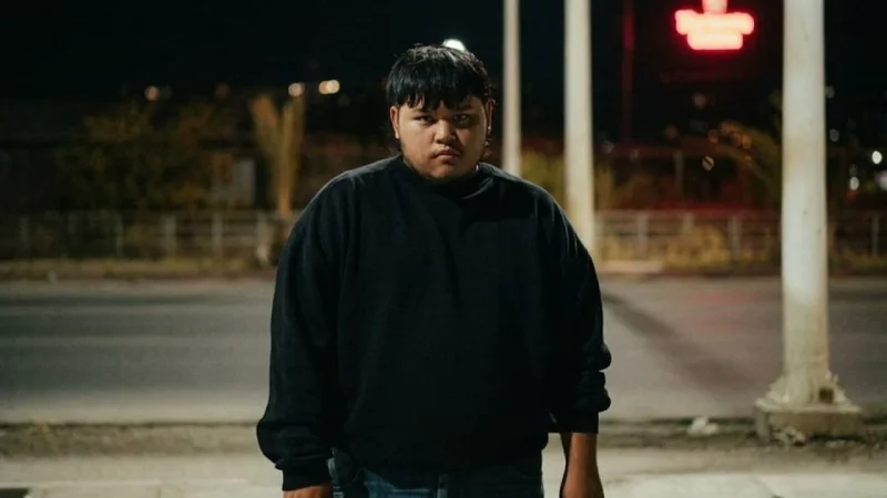 A person named Jezrelle standing outdoors at night wearing a black long-sleeve shirt