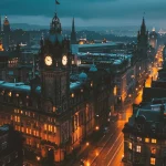 Evening cityscape with illuminated historic buildings and clock tower along busy street