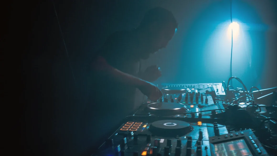 DJ mixing music on illuminated decks at a lively club event.