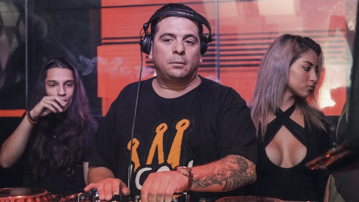DJ wearing headphones mixing tracks on decks at a lively club.