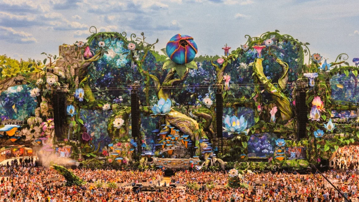 Elaborate fantasy music festival stage with giant flowers and a massive crowd.
