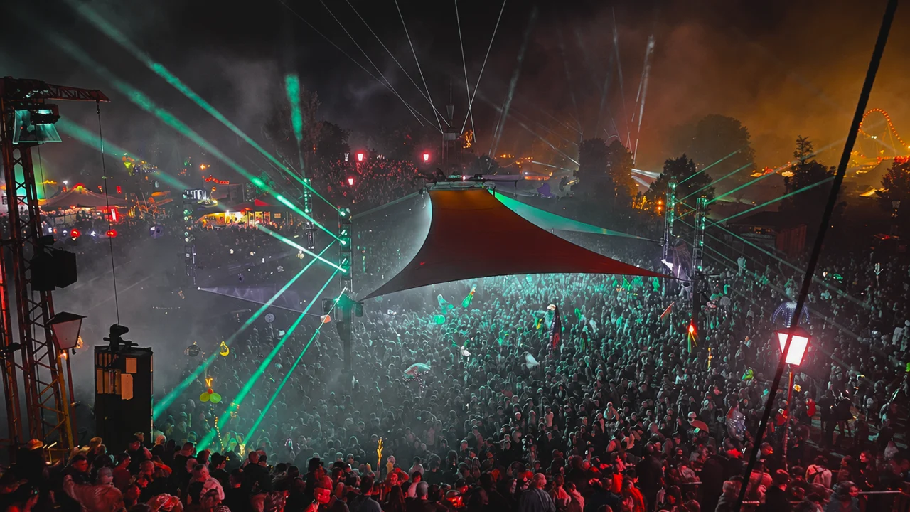 Large crowd enjoying a night music festival with bright green laser lights.