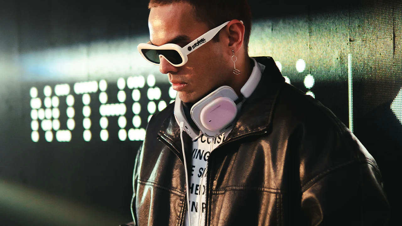 Hoest, DJ, Producer Stylish man with white sunglasses and pink Nothing headphones, black leather jacket.