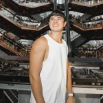 Happy DJ performing for energetic crowd at multi-level outdoor venue.